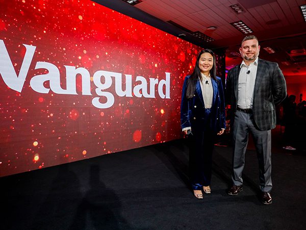 Vanguard_Social_WebContent_UnlimITed_Image01_600x450 Two presenters stand on the unlimITed stage in front of a large red display featuring the Vanguard logo and event branding.