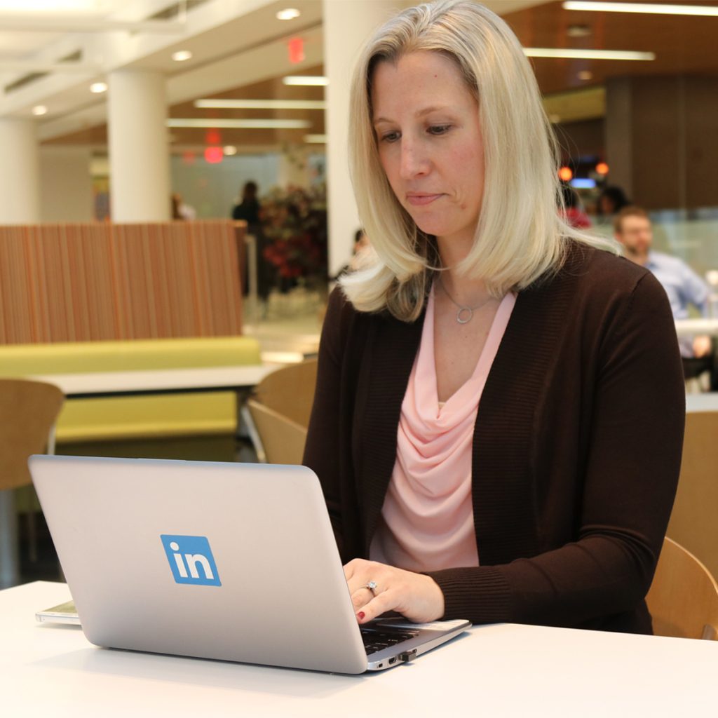 employee sitting at table and reviewing their social media profile on their laptop