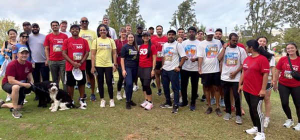 A group of Vanguard Dallas crew standing together after participating in the 2025 Texas Strong Start for Kids 5K as part of the Community 365 campaign. Many are wearing red Vanguard t-shirts, and a dog is in the front row of the group picture.