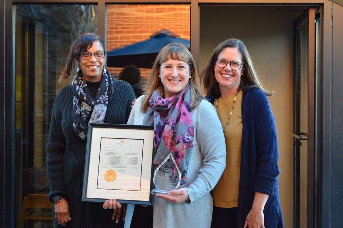 Lara D. holding the Pennsylvania Governor’s Victim Service Pathfinder Award and posing with two people