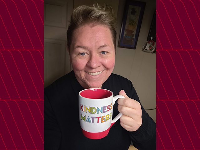 Shawn H. holding mug that says "Kindness Matters"