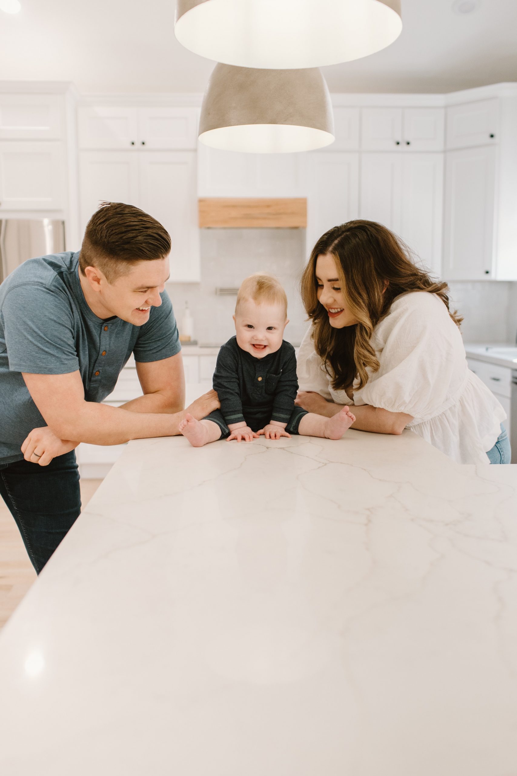 Hailee B. with husband and son smiling while sitting on counter