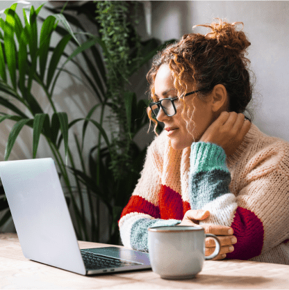 Woman seated, staring at her laptop screen.