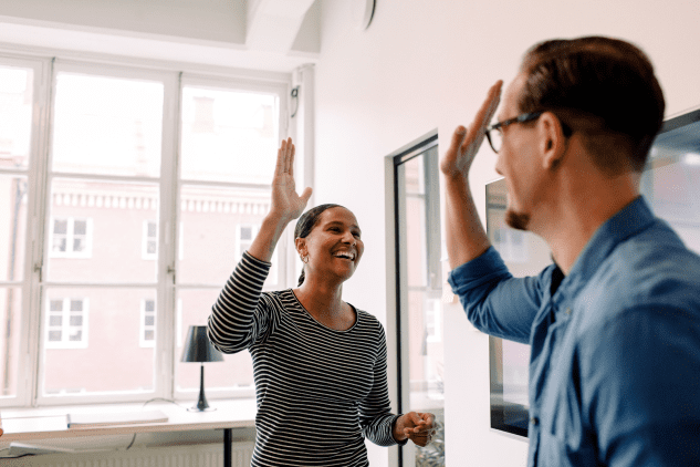 Man and woman giving each other a high-five and smiling.