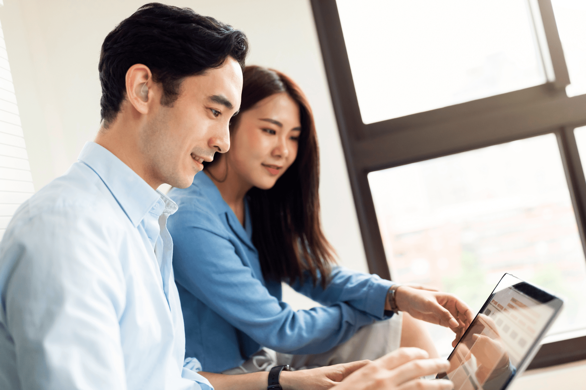 Man and woman sitting and looking at a laptop screen together.