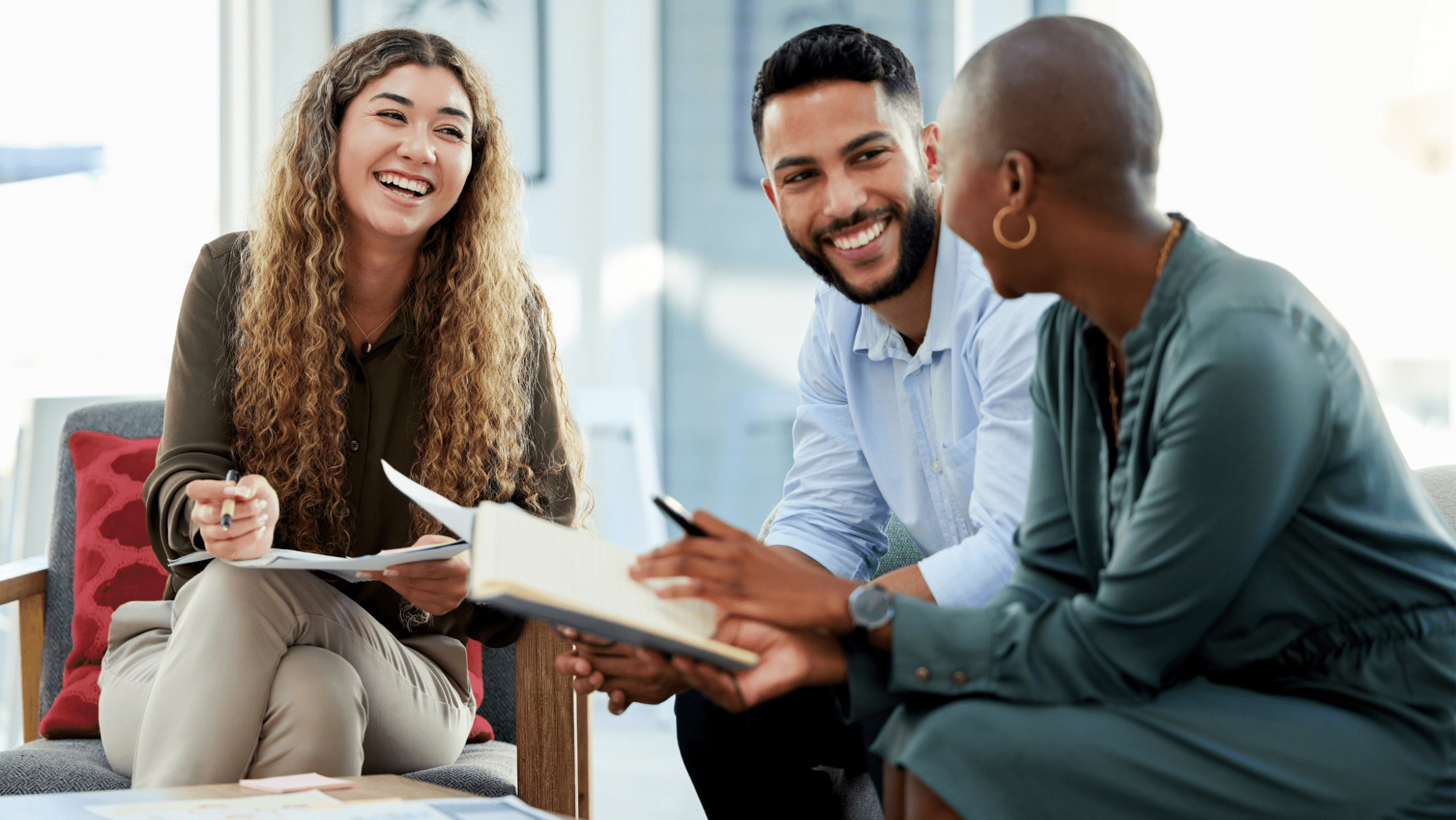 Three coworkers sitting and laughing together in a common area in the office.