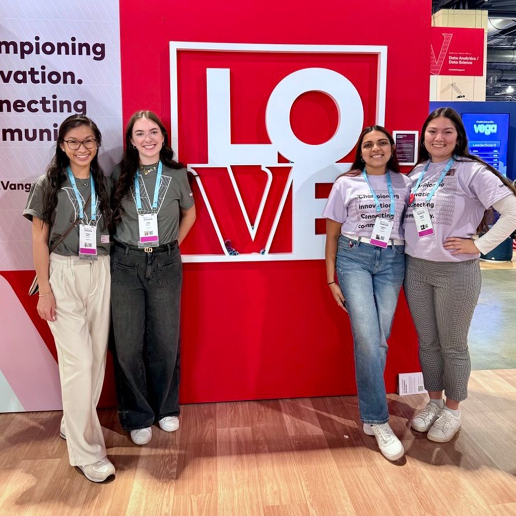 Justina (far left) and fellow Technology Leadership Program participants at Grace Hopper conference posing in front of Vanguard’s booth. 
