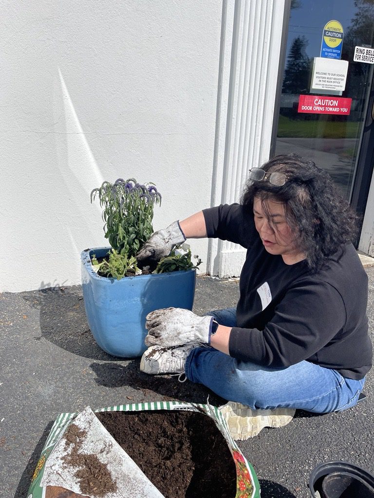 Amy sitting on ground placing mulch in plant