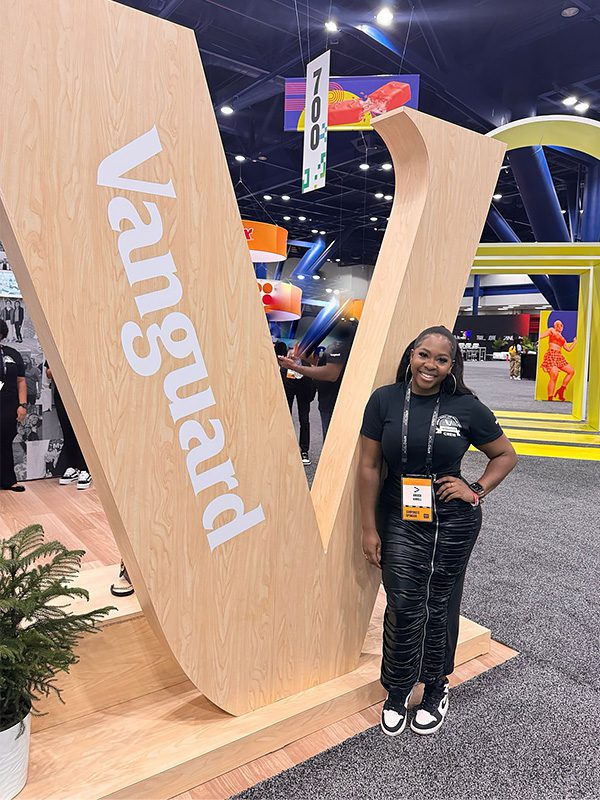 Amber standing next to Vanguard sign in booth at AfroTech Conference