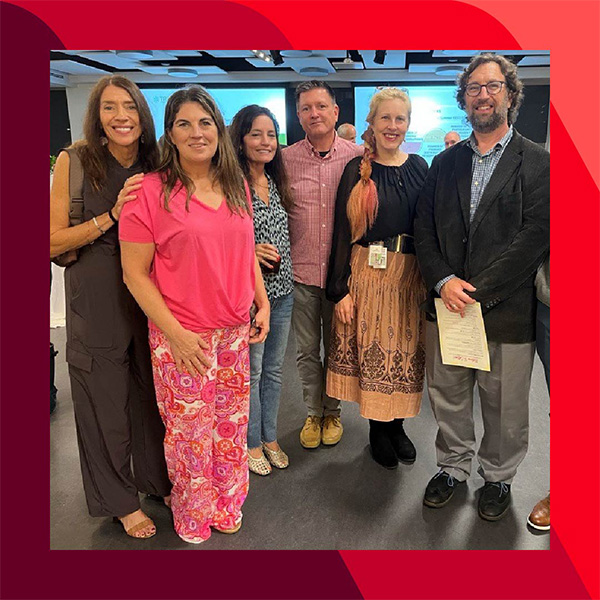 Angela and others stand together in a room, posing for a group photo.